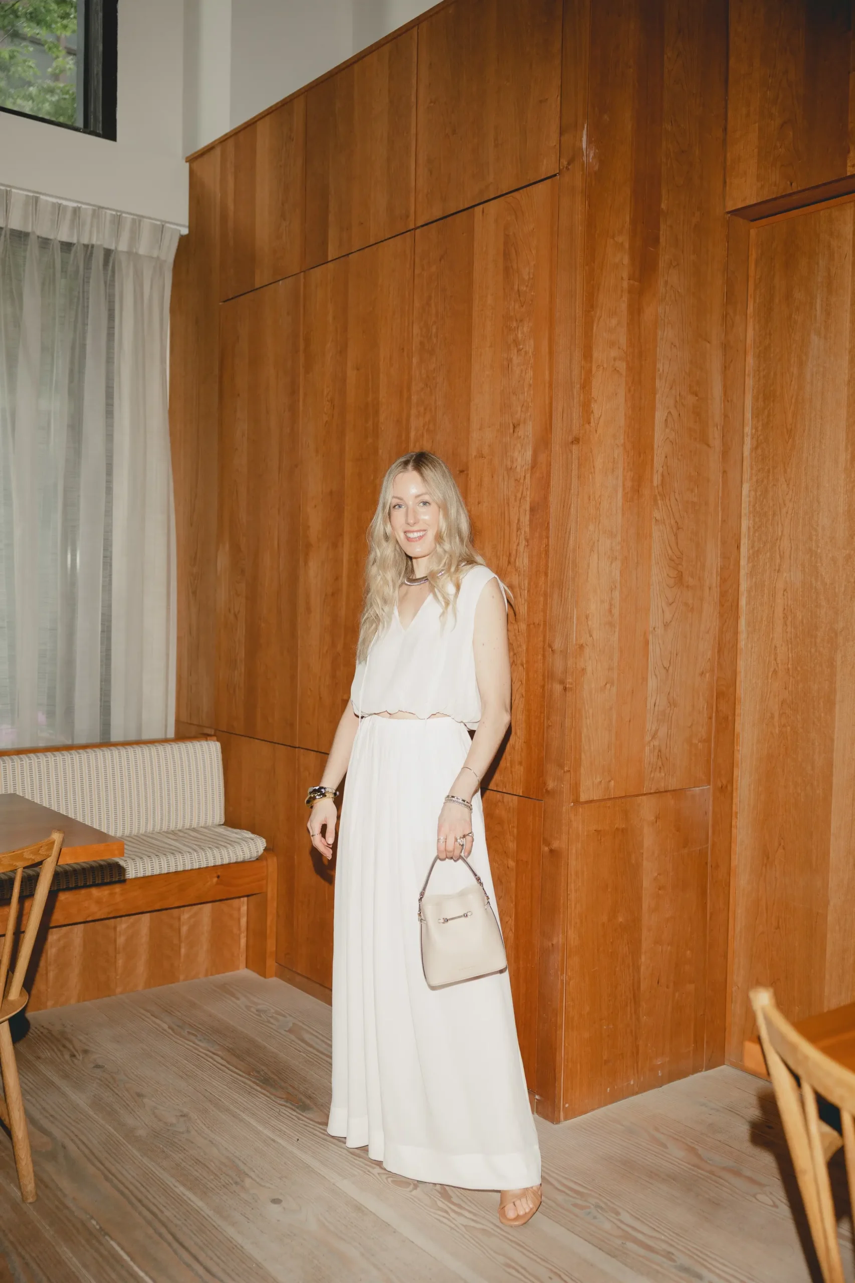 Personal stylist wearing a neutral white outfit in a warm wood-paneled interior